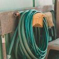 Green and yellow garden hose coiled on a wooden table
