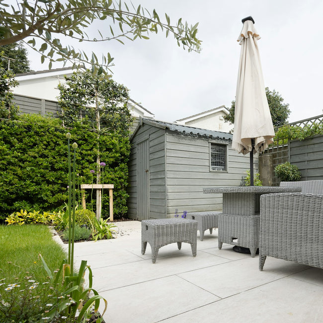 Patio dining table and chairs shaded by an umbrella